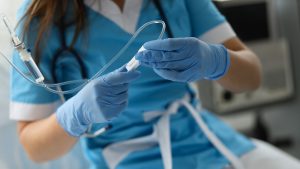 Prince Edward Island College of Nursing and Midwifery. Nurse wearing surgical gloves holding a drip. 